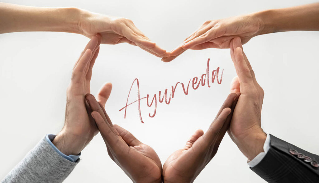Haende die ein Herz formen mit dem Wort Ayurveda in der Mitte